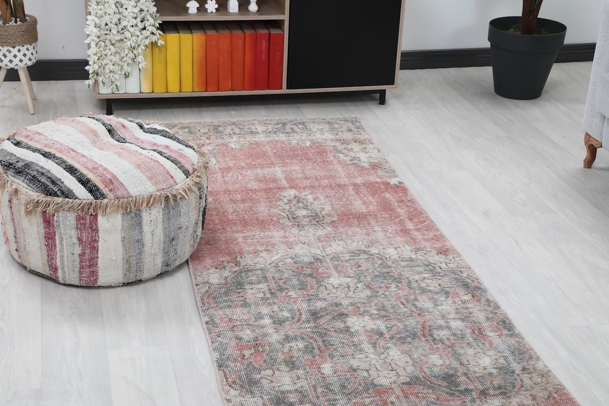 Close-up of the rug's pattern and colors next to a striped ottoman.