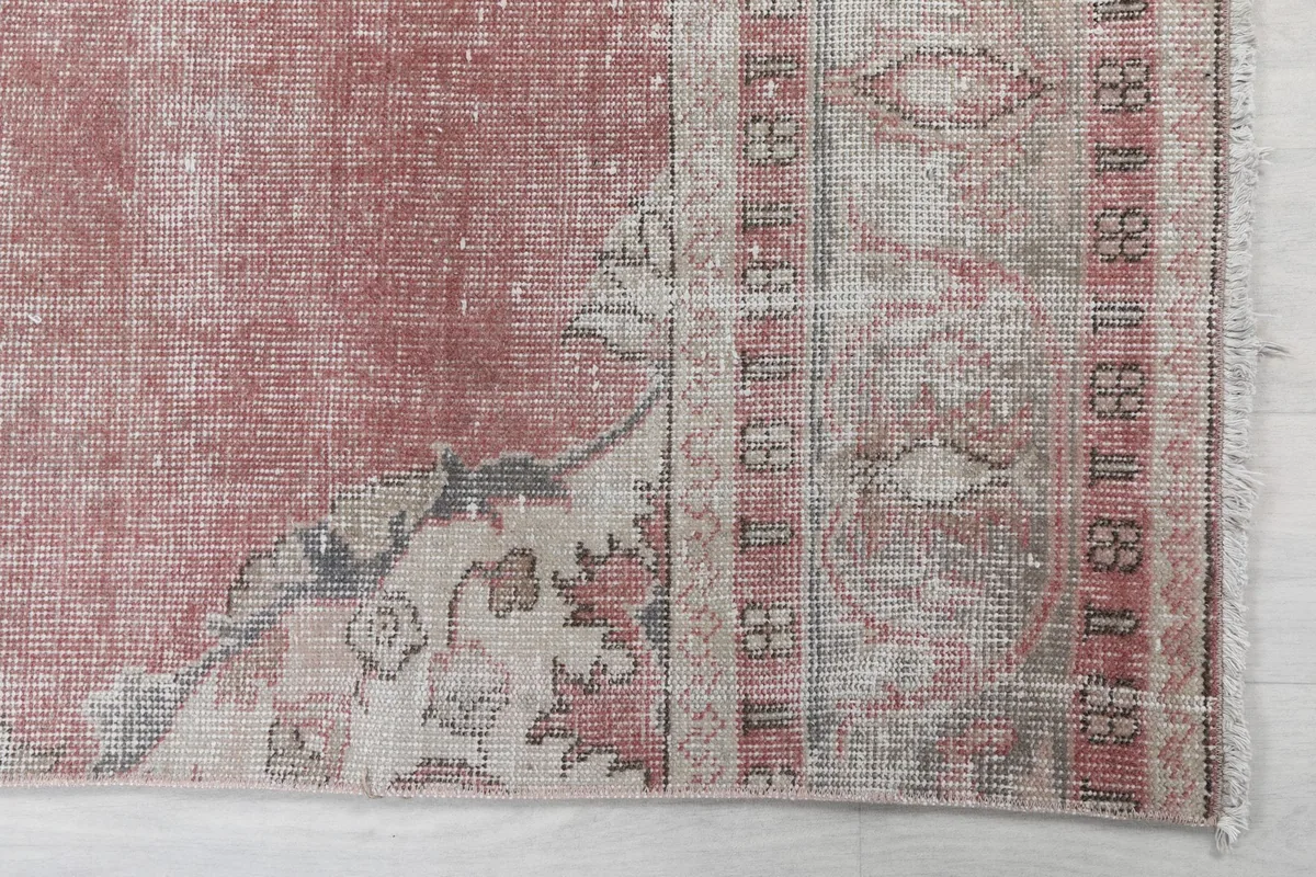 Detail of the rug's border design and field color in rose and ivory.