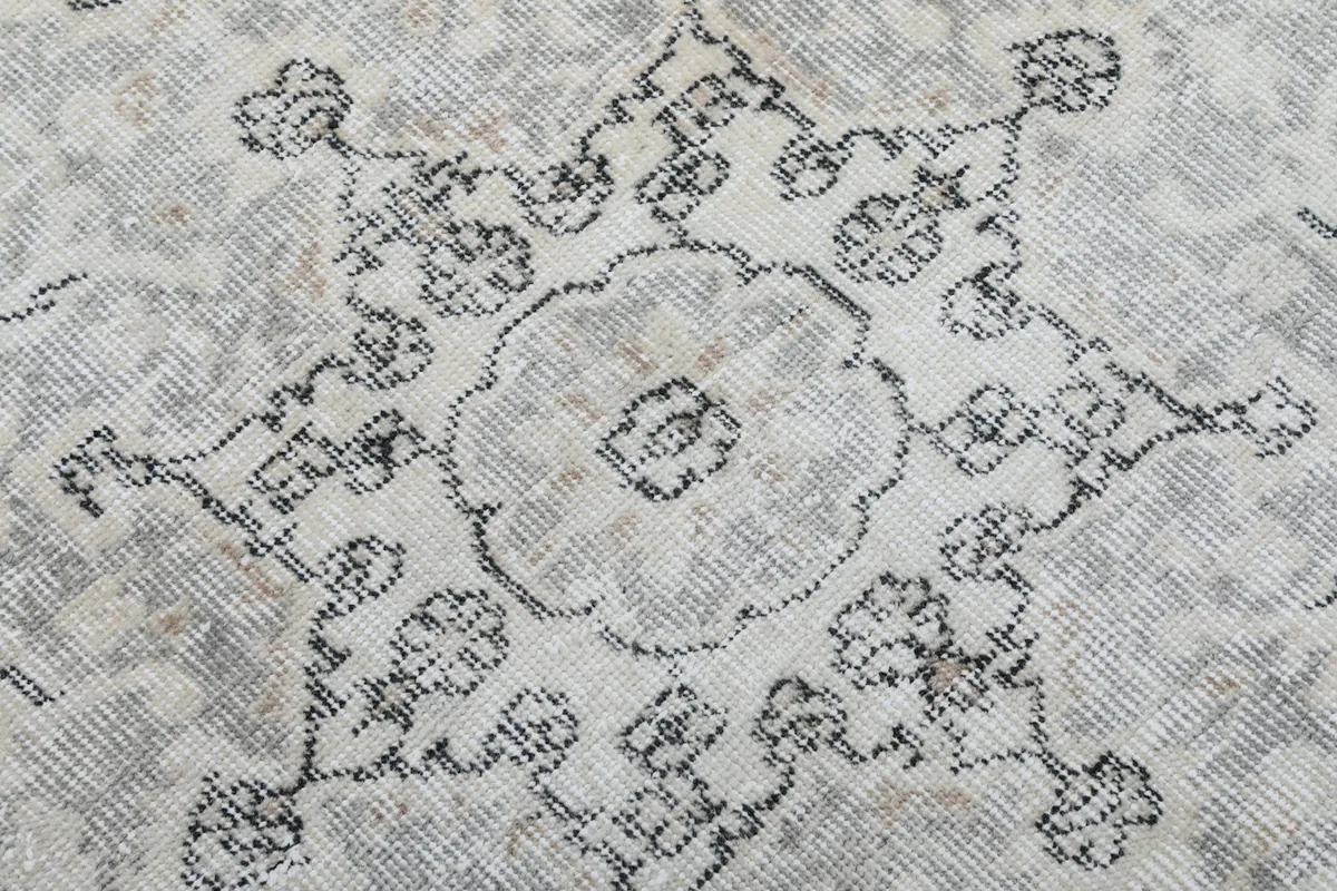 Close-up of the distressed wool pile and charcoal floral motifs within the medallion