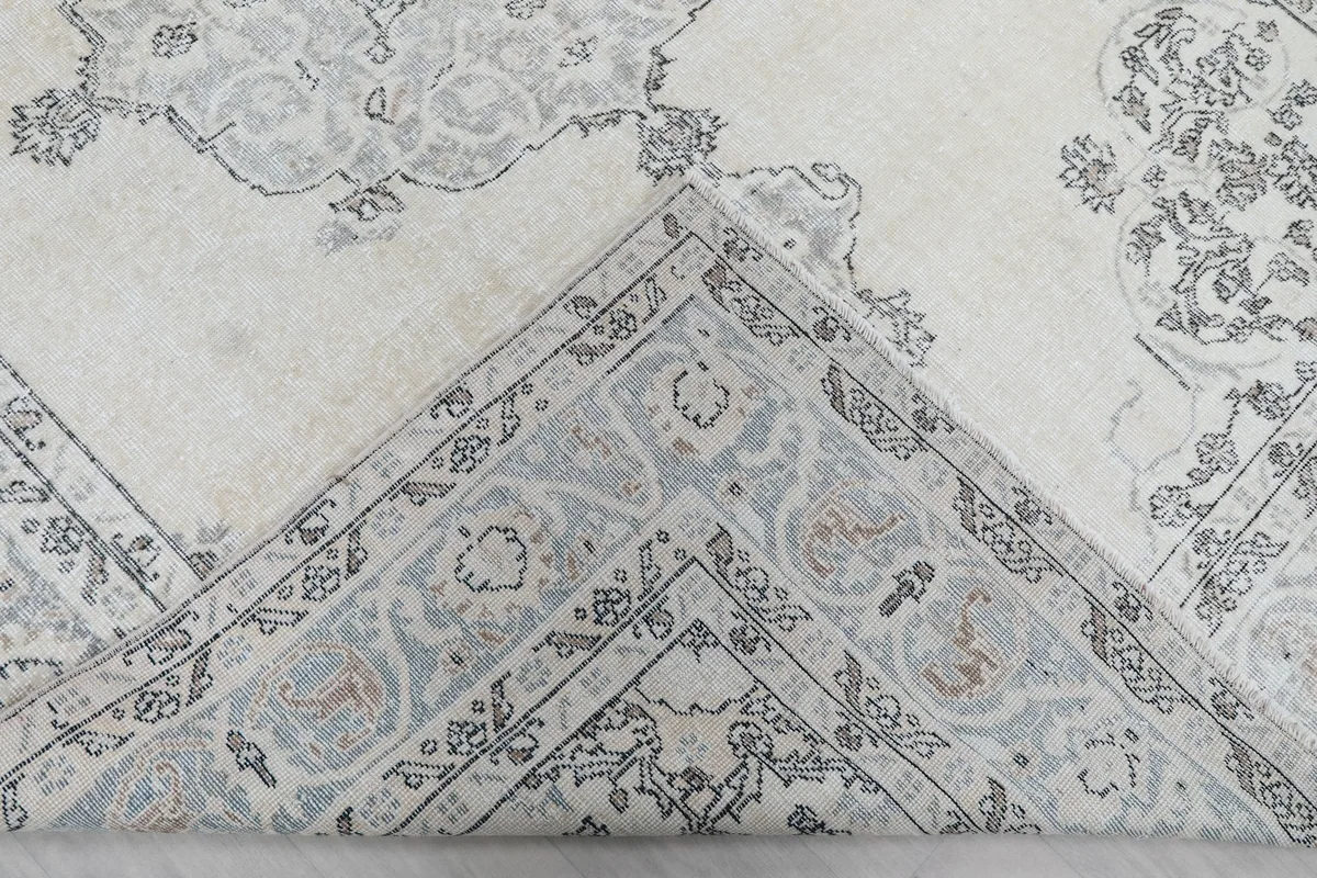 View of the rug's underside, revealing the hand-knotted cotton foundation and some blue fibers