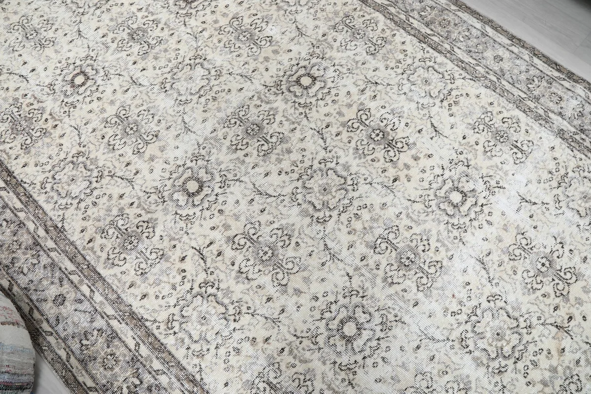 Overhead detail shot highlighting the repeating ivory and gray patterns across the rug's field