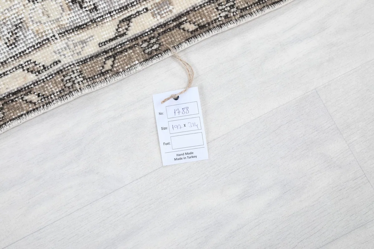 Tag indicating the rug's origin and size, placed on the floor next to the rug