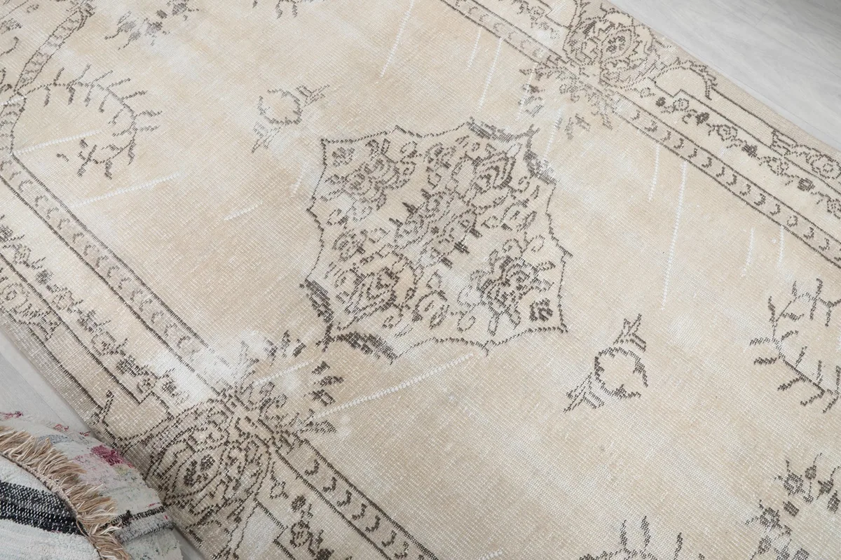 Angled view of the central medallion and surrounding motifs on the ivory vintage rug