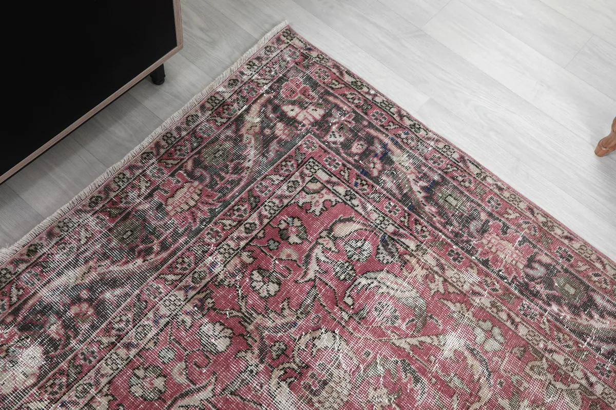 Corner view of the rug, showing the blend of rose, navy, and beige tones