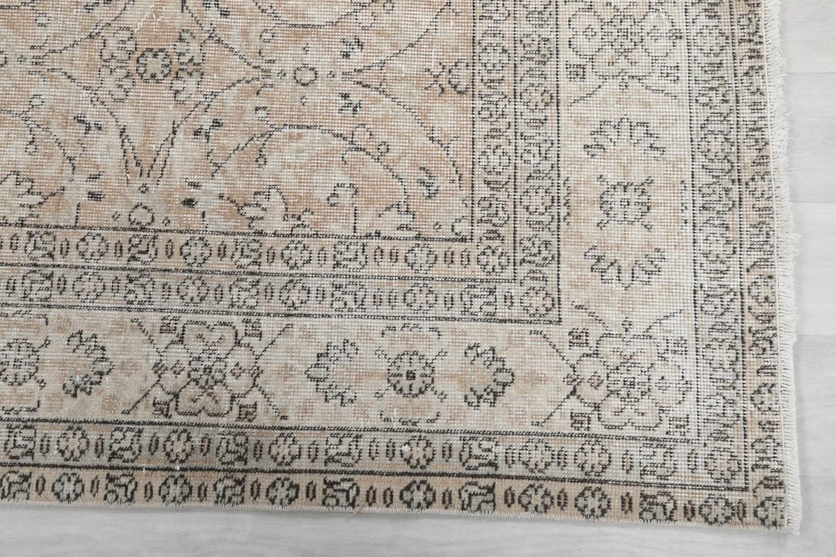 Detailed view of the intricate gray border design and corner of the vintage rug