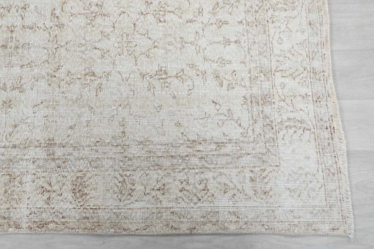 Close-up of the rug's border, revealing faded floral and geometric details.