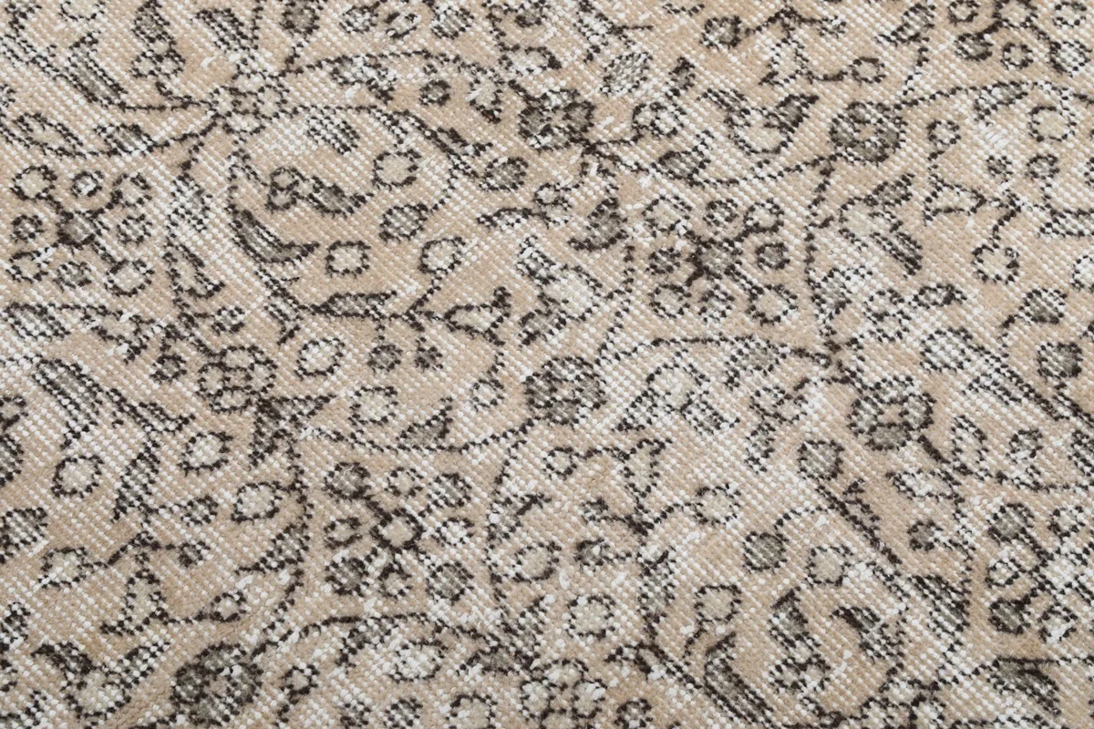 Close-up detail of the hand-knotted wool pile and intricate gray botanical motifs
