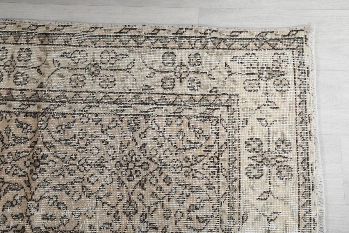 Detail of the rug's corner with the gray floral and geometric border design