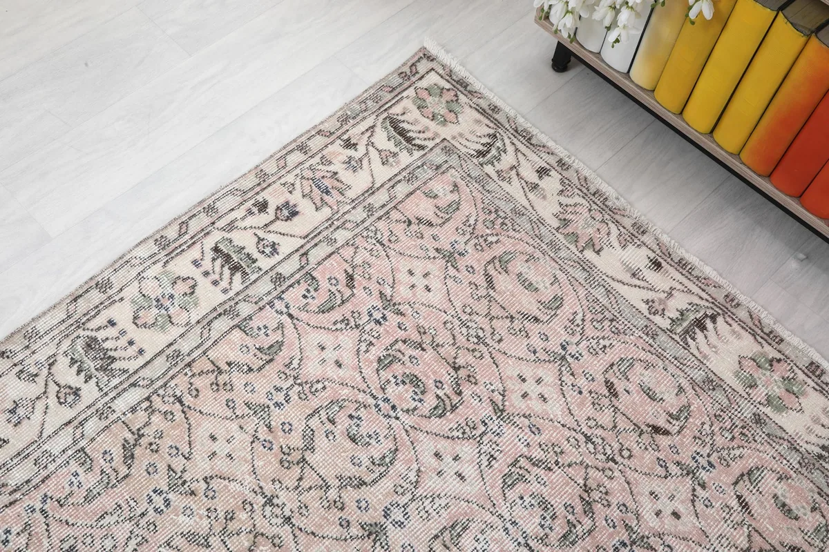 Corner view of the rug, showing the blend of rose field and ivory border