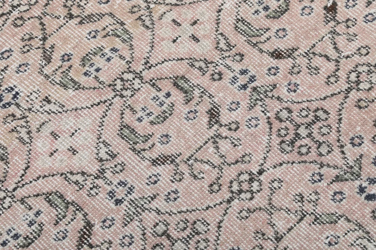 Close-up view of the wool pile texture and faded rose and gray colors