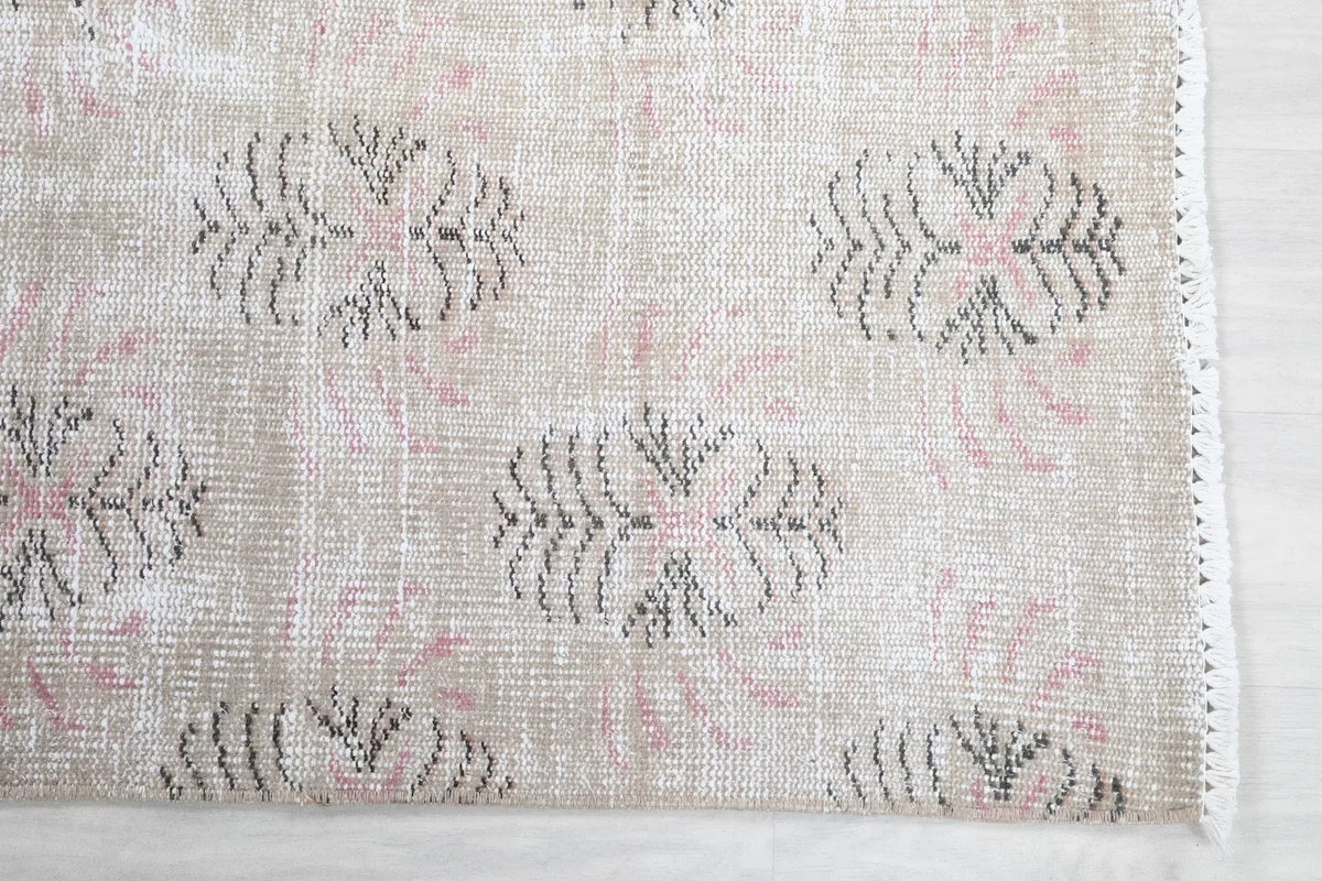 Close-up of the rug's edge and a gray floral motif with a touch of rose color