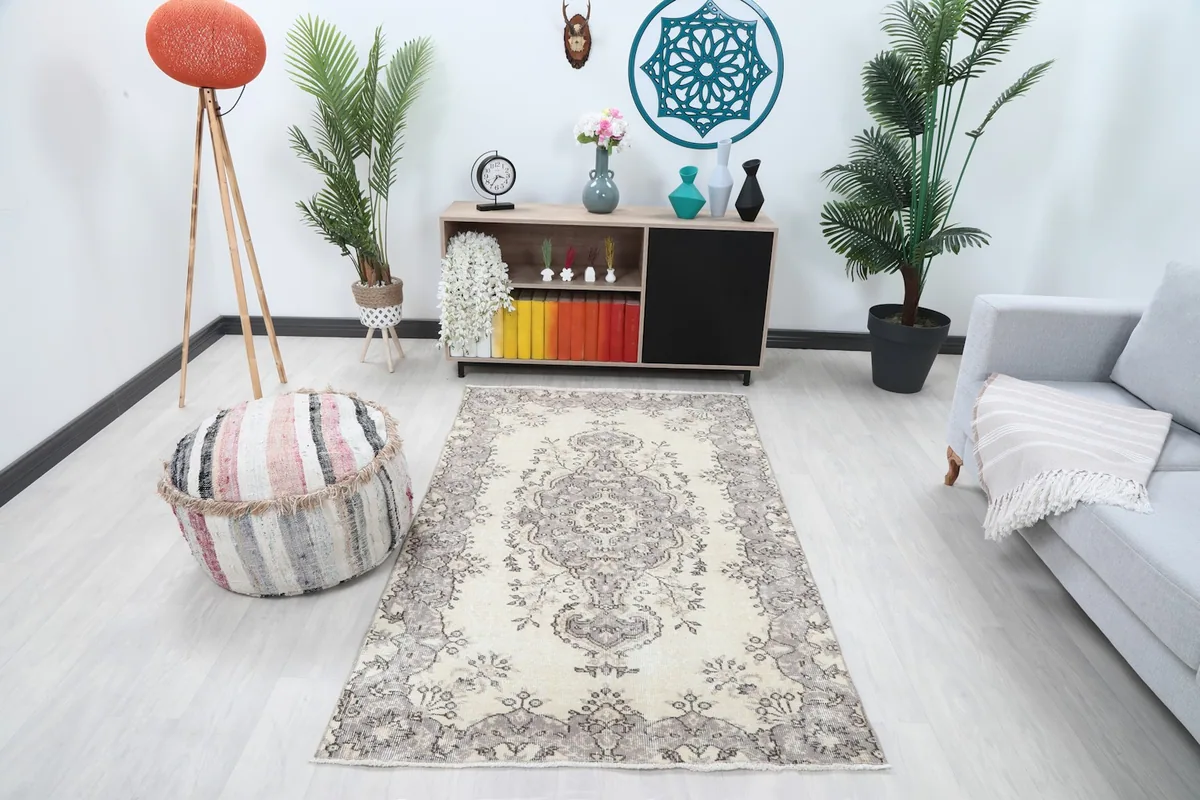 Ivory and gray rug in a living room setting with a light gray sofa and striped pouf