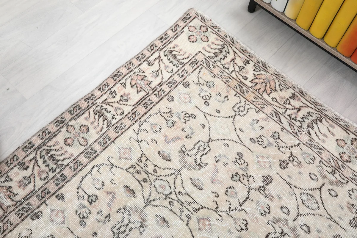 Angled view of the rug's field and border, showing the faded colors and hand-knotted details.
