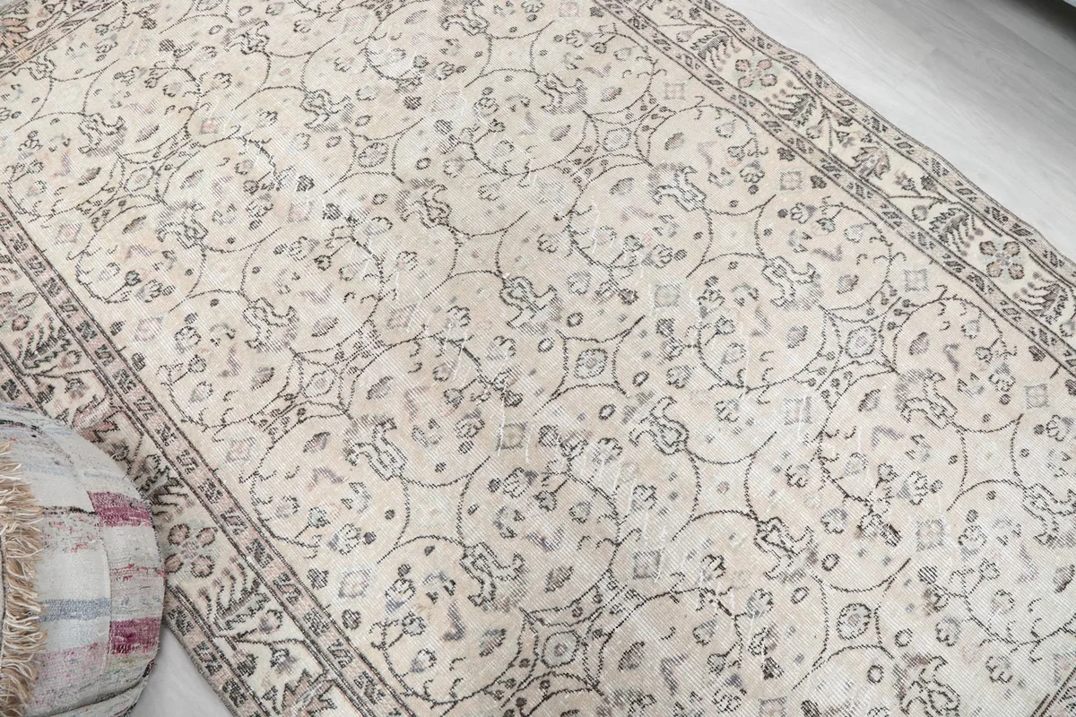 Overhead view of a section of the beige rug, highlighting the circular floral designs and low pile.