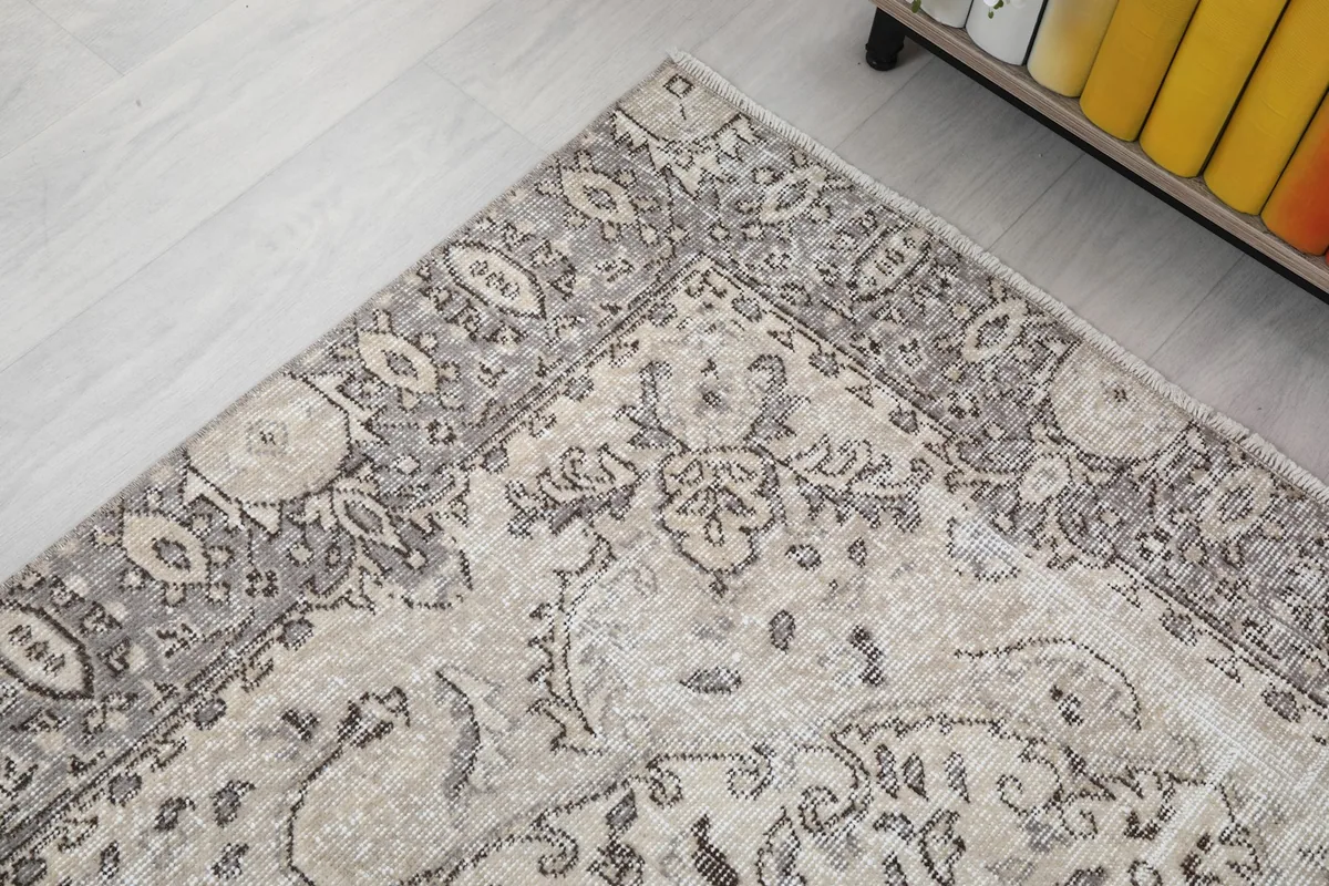 Corner detail of the rug, highlighting the transition from the cream field to the gray border