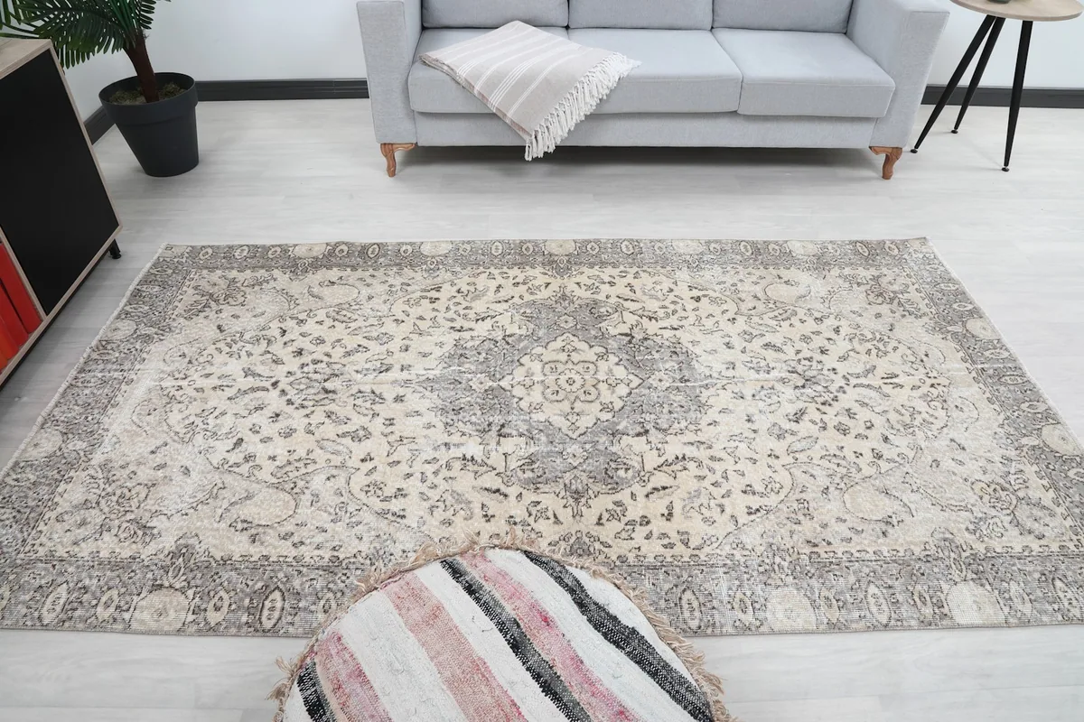 Full room view of the vintage rug, centered with a gray sofa in the background