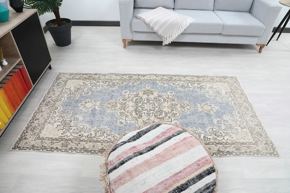 Rug placed in a room, providing a sense of scale with a sofa and ottoman nearby