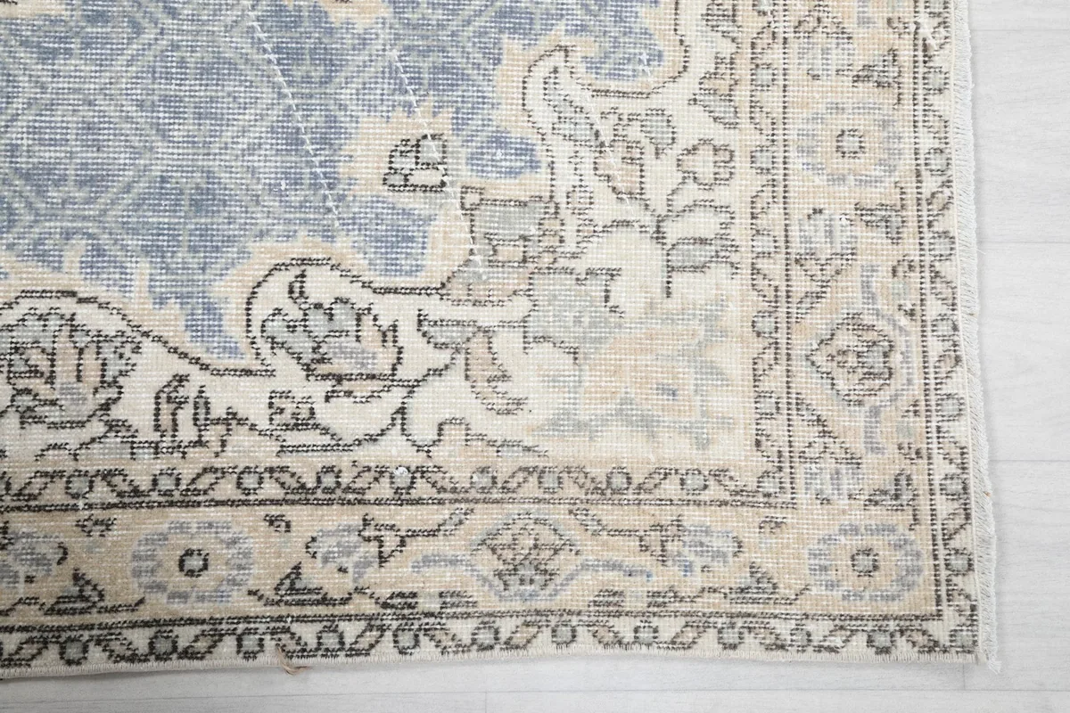 Detailed view of the rug's border design and corner, highlighting the ivory and blue colors