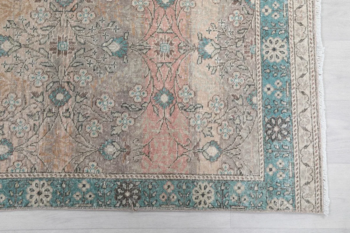 Detailed view of the rug's patterns and border, showing faded rose and blue tones.