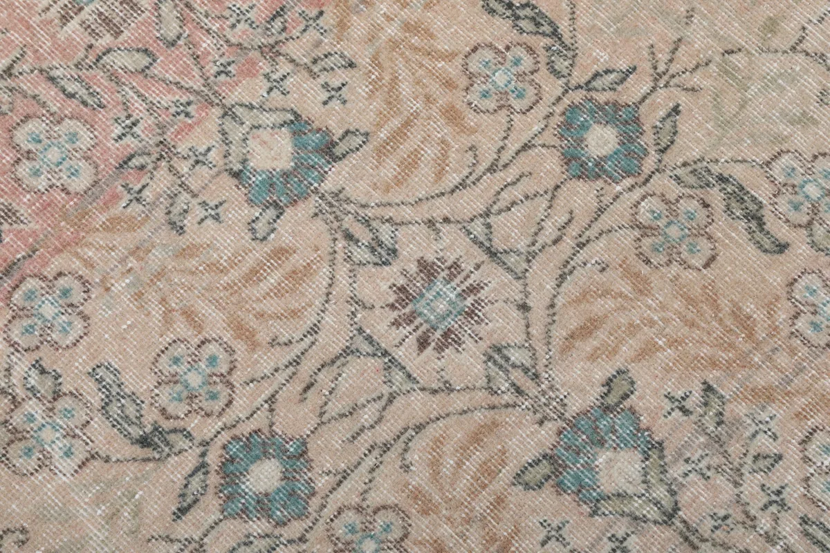 Extreme close-up of the wool pile and intricate floral patterns in beige, rose, and blue.