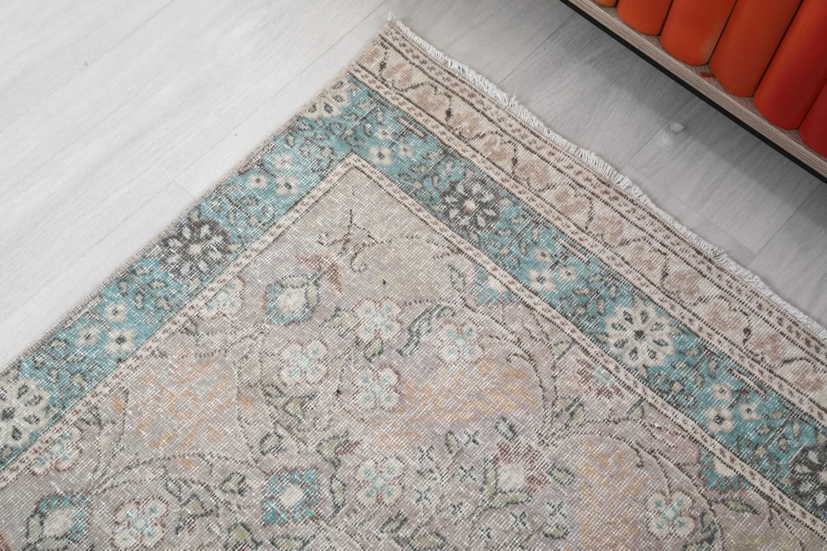 Corner detail of the rug, focusing on the blue border and the transition to the beige field.