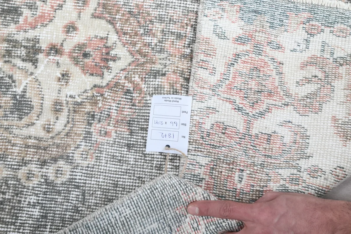 Detail showing the rug's tag with item information and a hand pointing to the texture