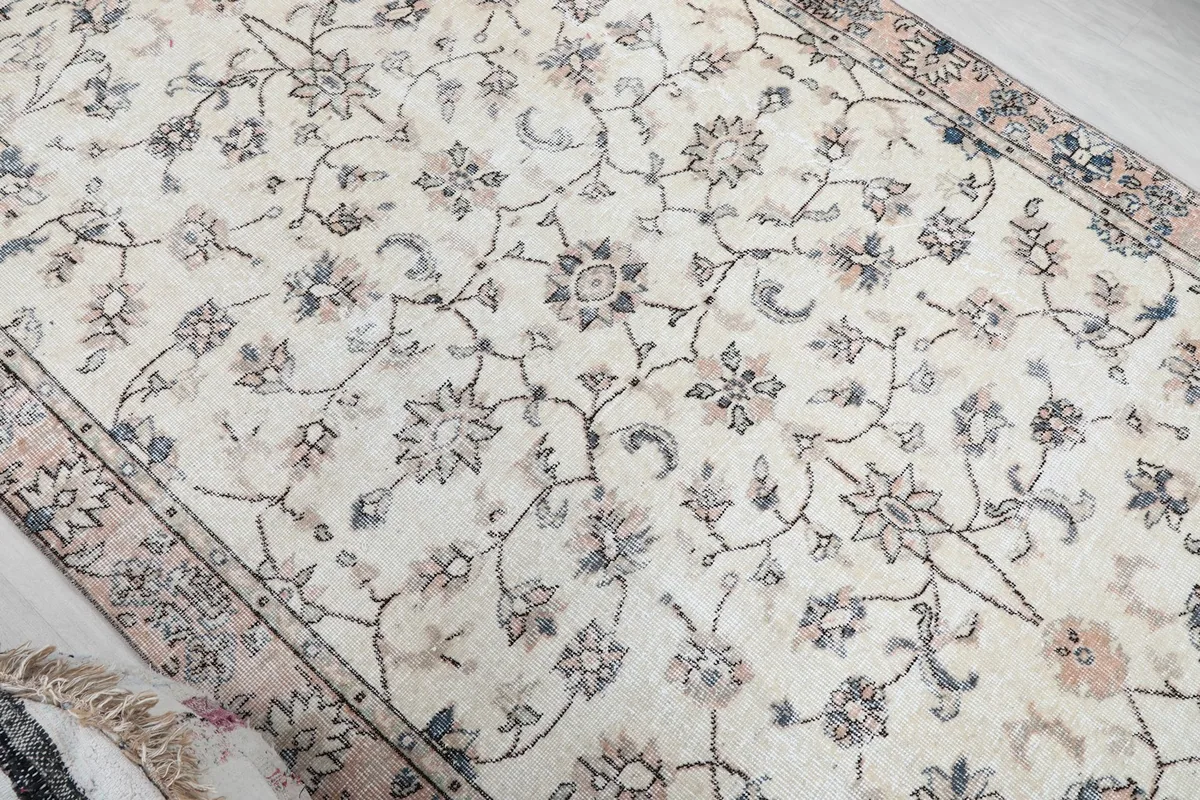 Overhead angle showing the texture and pattern of the hand-knotted wool pile on the cream rug