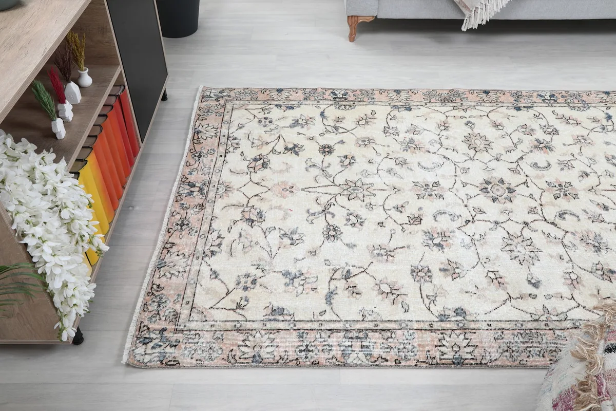 Wide angle view of the cream and rose rug in the living room, emphasizing its medium size