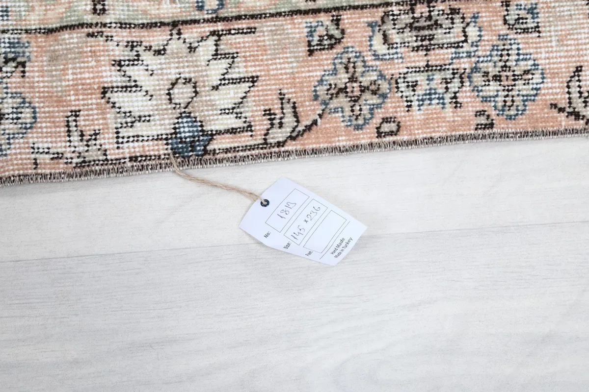 Detail of the rug's edge with a tag, confirming the hand-knotted wool construction and origin