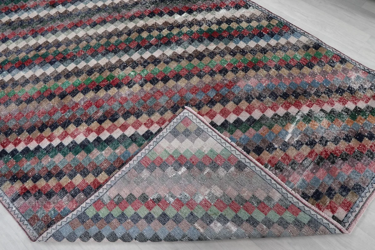 Corner of the rug folded back, revealing the cotton foundation and reverse side of the hand-knots