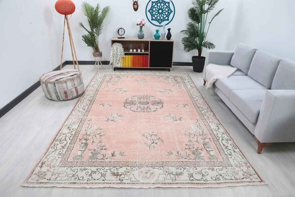 Large rose vintage rug displayed in a modern living room setting with a gray sofa