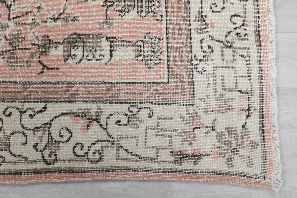 Detailed view of the rug's ivory border with intricate gray geometric and floral patterns