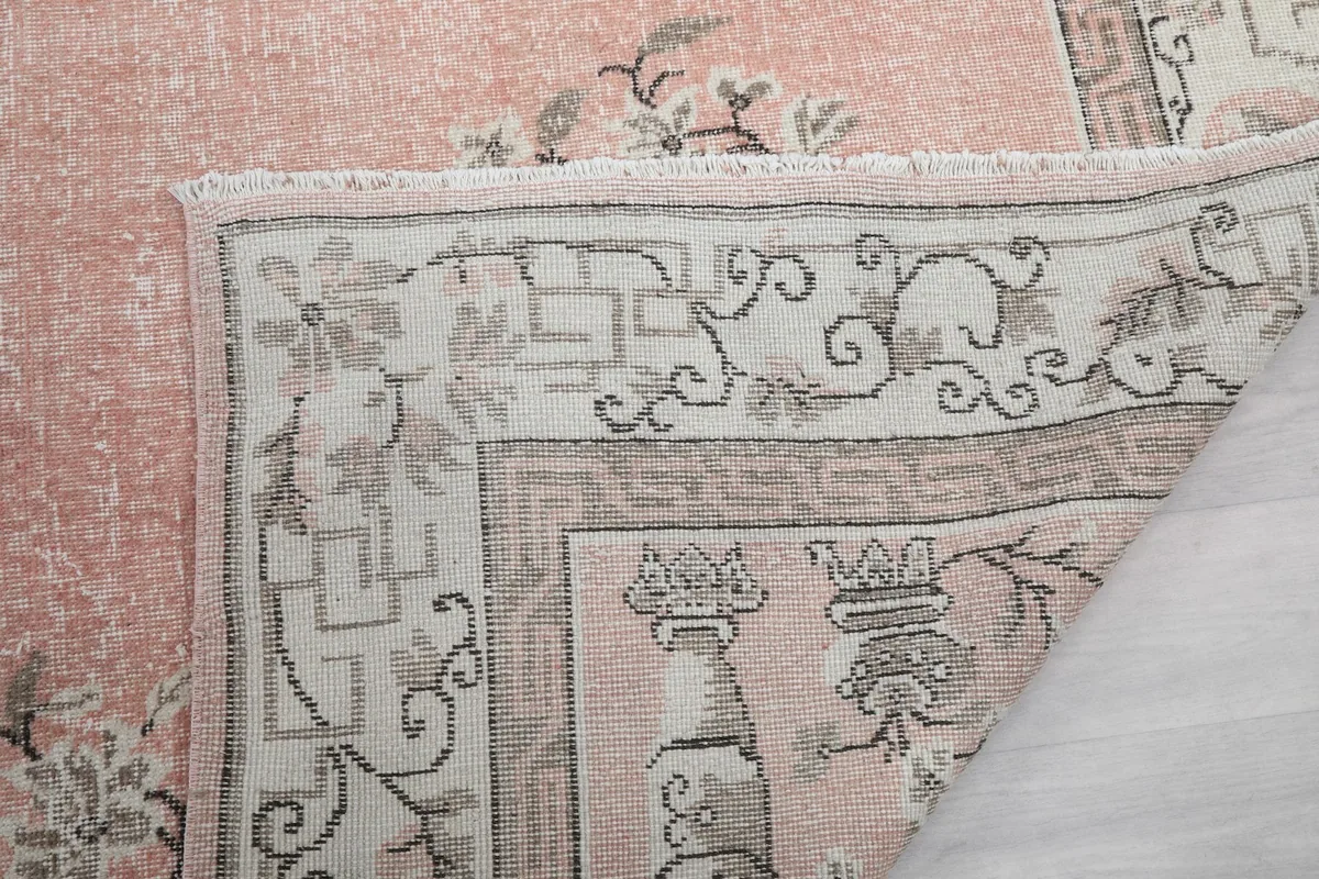 Close-up of the rug's corner with fringe and a glimpse of the back of the hand-knotted pile