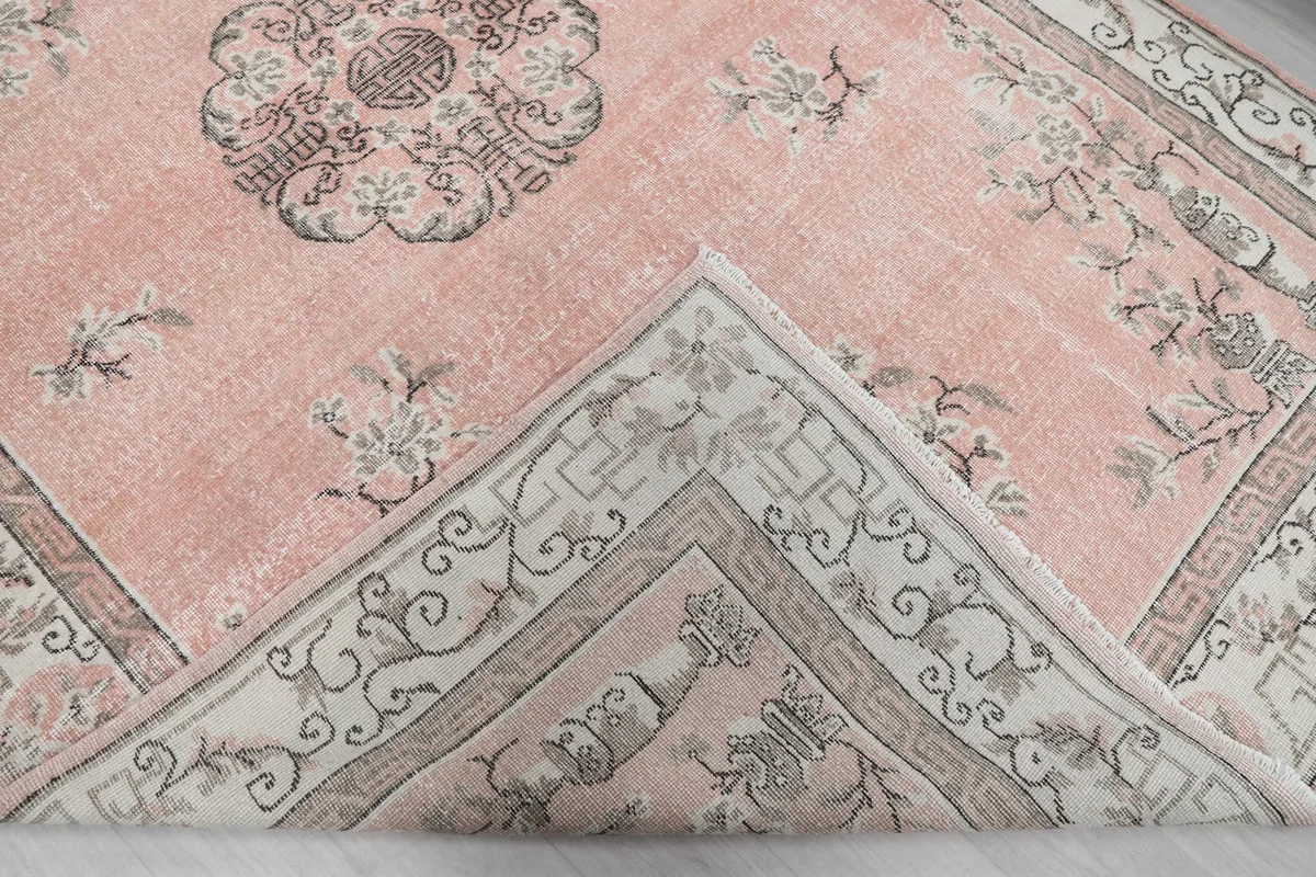 Corner of the rug folded back, revealing the reverse side of the hand-knotted construction