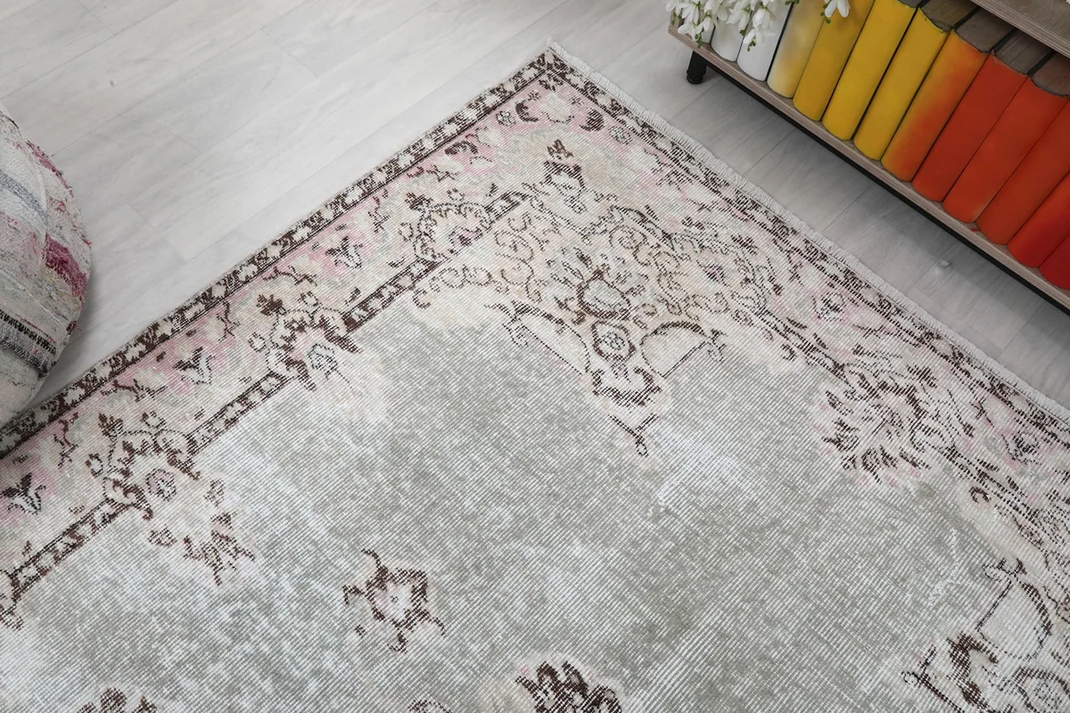 Diagonal view of the rug's corner, showing the gray field and patterned border