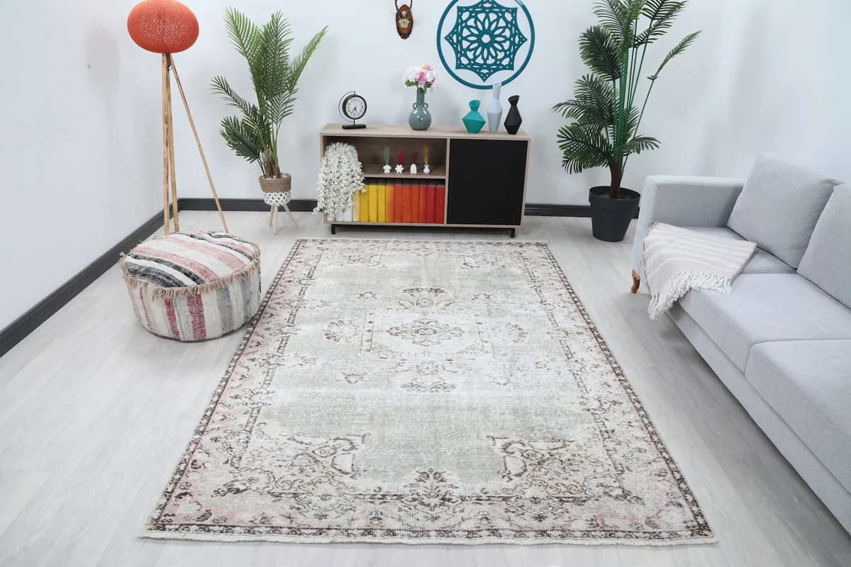 Vintage gray and rose rug in a living room setting with a sofa and pouf
