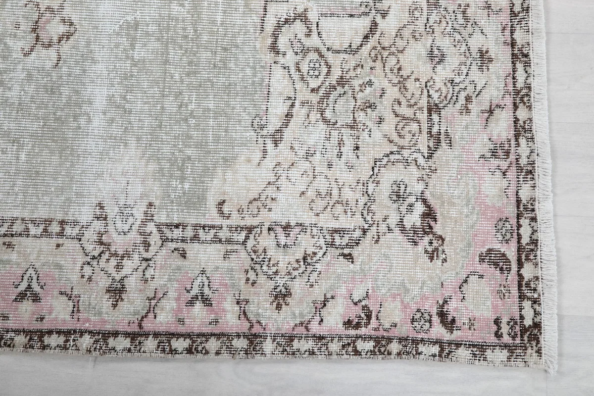 Detail of the rose and brown patterned border of the vintage gray rug