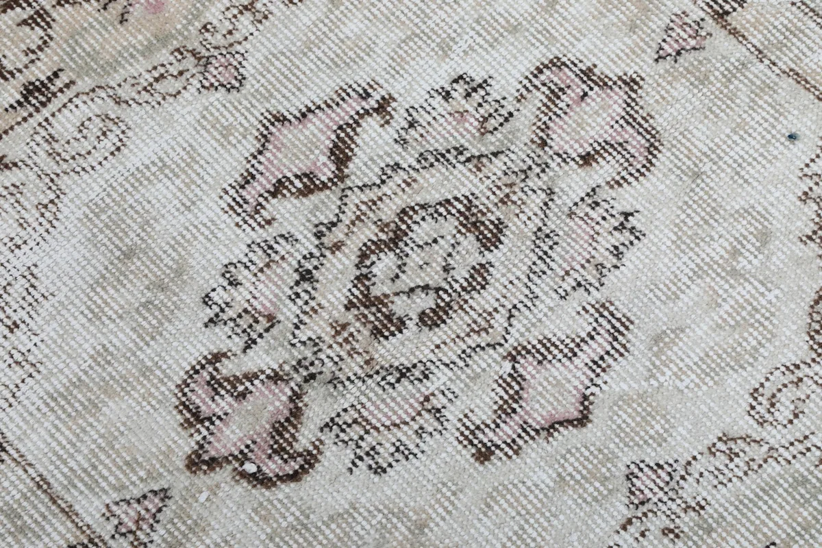 Texture and low pile of the hand-knotted wool rug, showing a worn motif