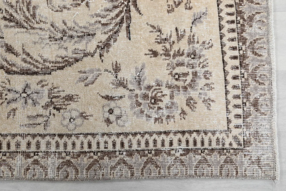 Detailed view of the rug's corner showing gray floral border and beige field