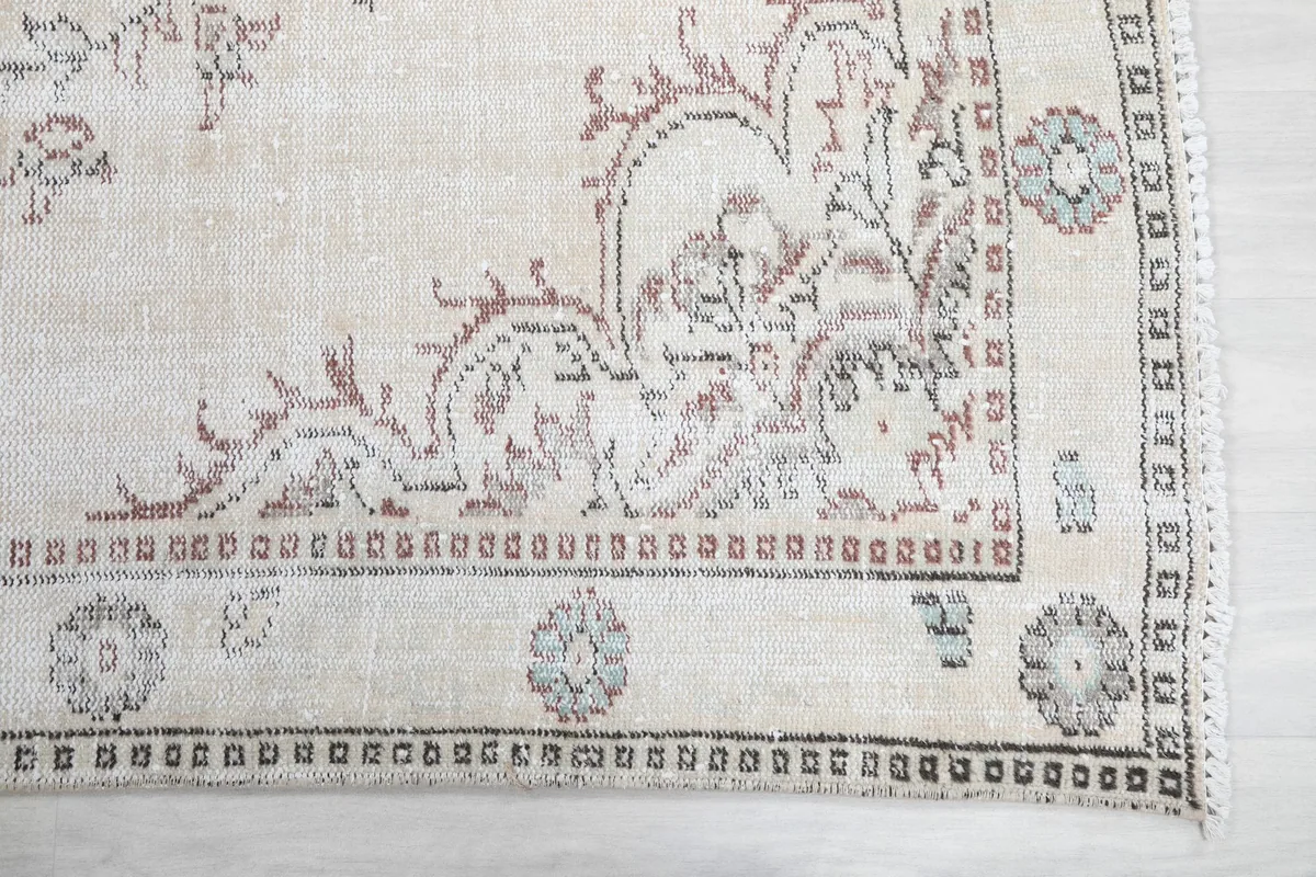Detailed view of the rug's border and corner motifs, showing subtle gray and rose colors