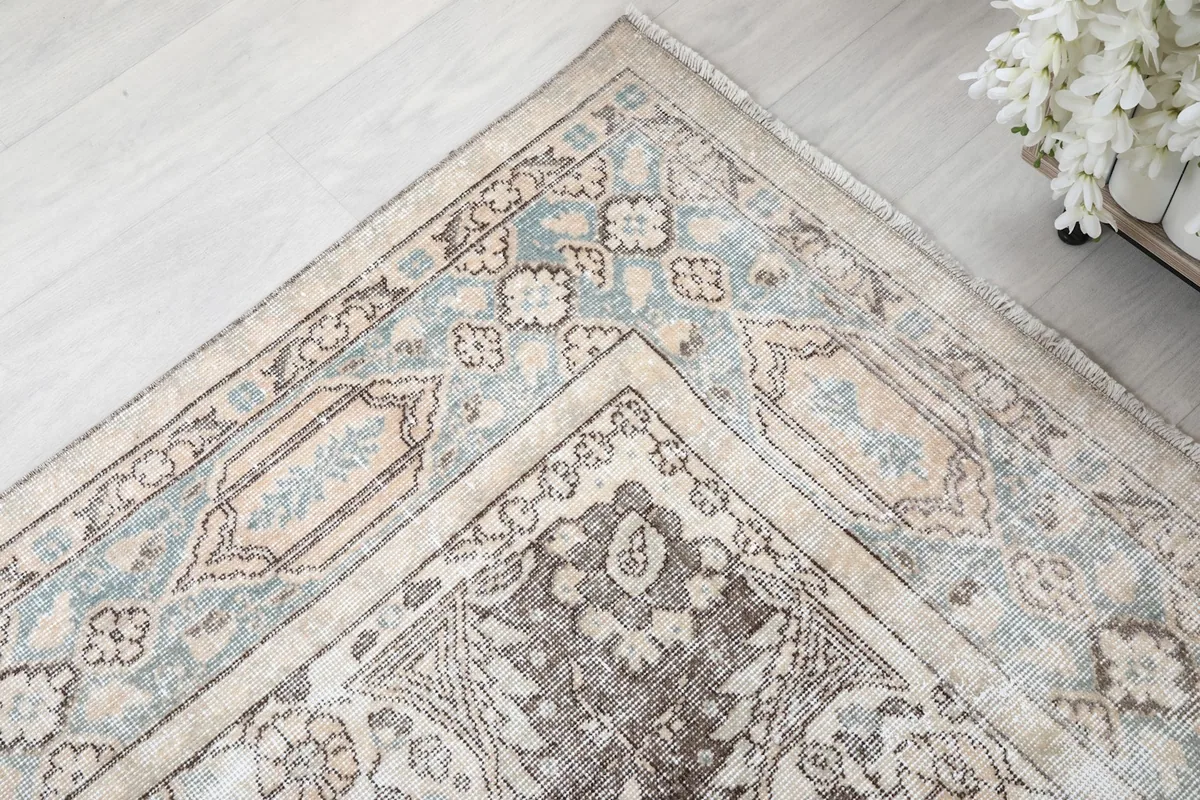 Corner detail of the rug showing the layered border design in beige, gray, and blue