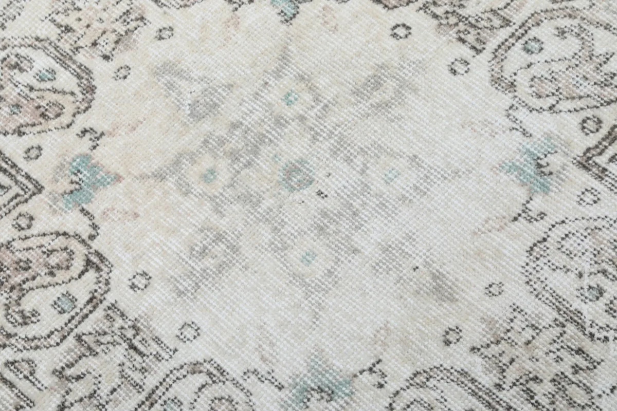 Texture and low pile of the vintage wool rug, showing faded gray and blue tones