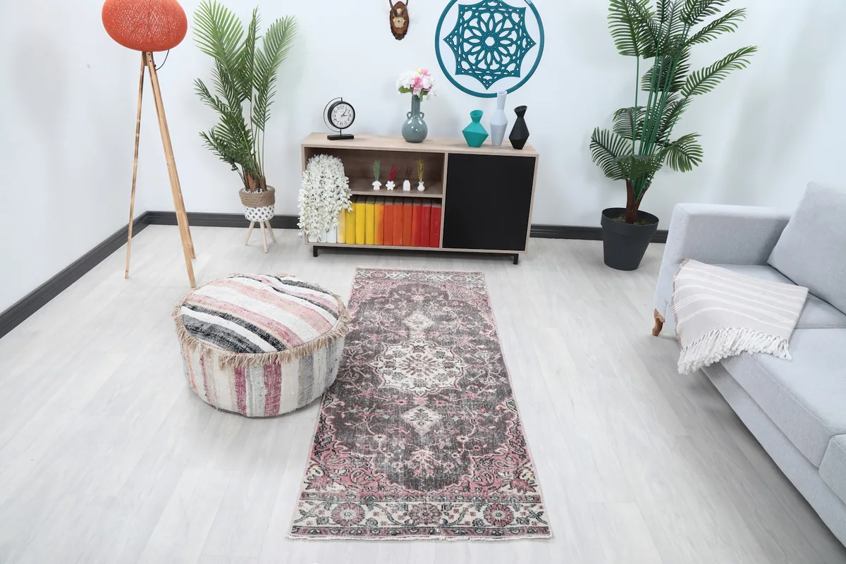 Runner rug in a modern living space with a gray sofa and striped ottoman, showing its full length