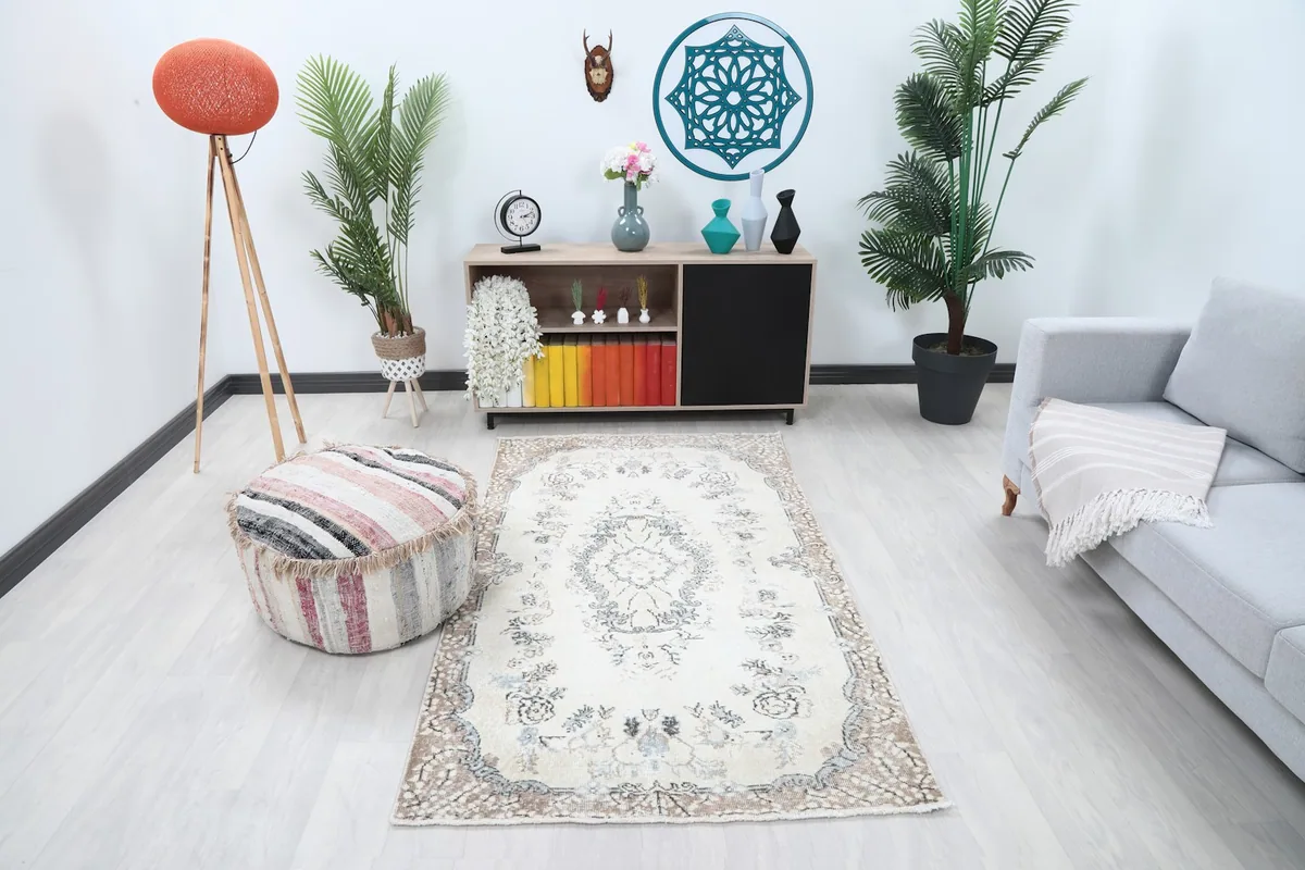 Ivory floral medallion rug in a living room setting with a light gray sofa and wooden furniture