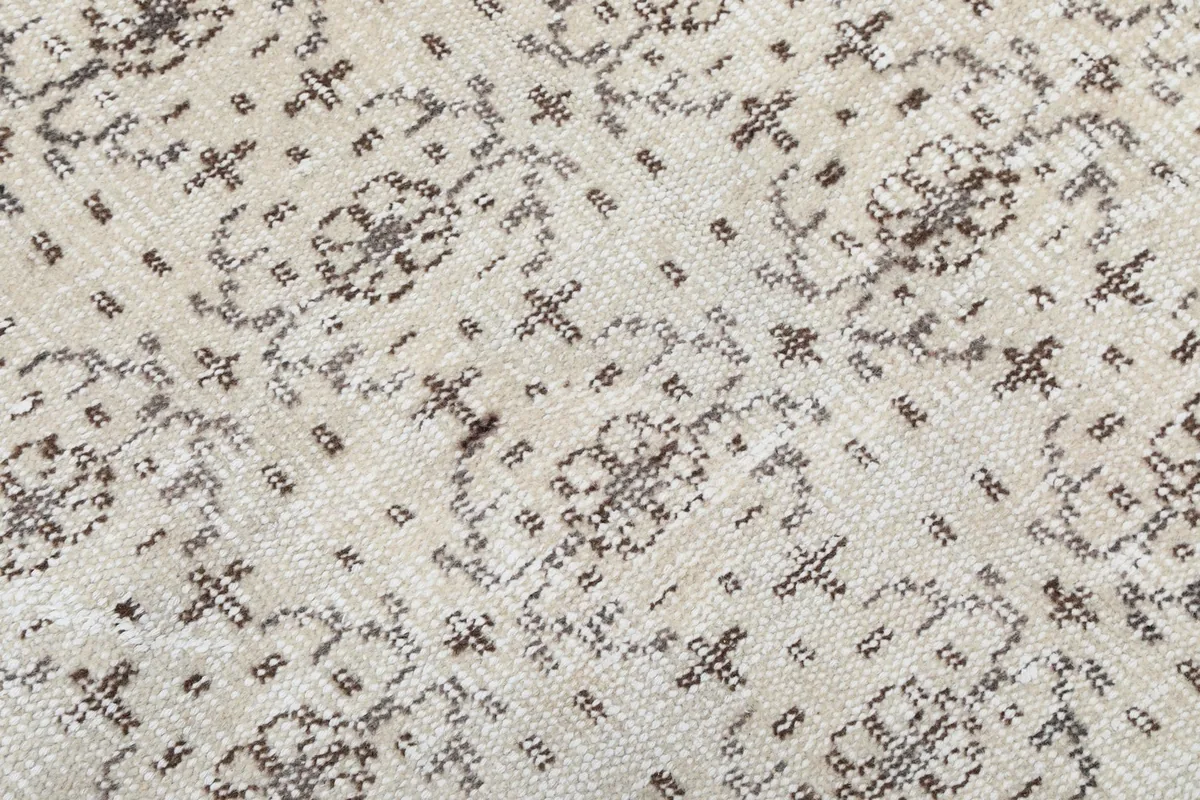 Close-up of the low pile texture and subtle wear on the vintage wool rug's surface