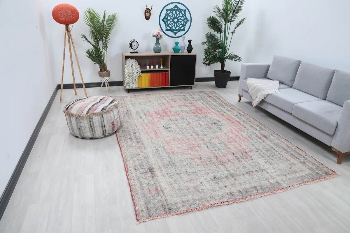Angle view of the faded rose and gray rug in a living space, showing its distressed pattern.