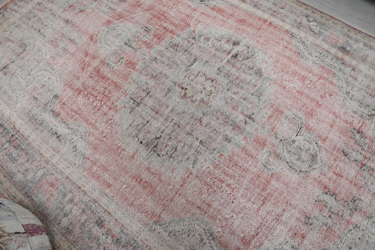 Close-up of the distressed medallion pattern and low pile texture on the vintage rug.