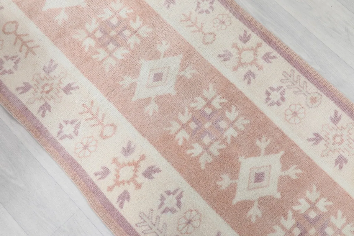 Angled view focusing on the central rose field and ivory border with tribal geometric patterns.