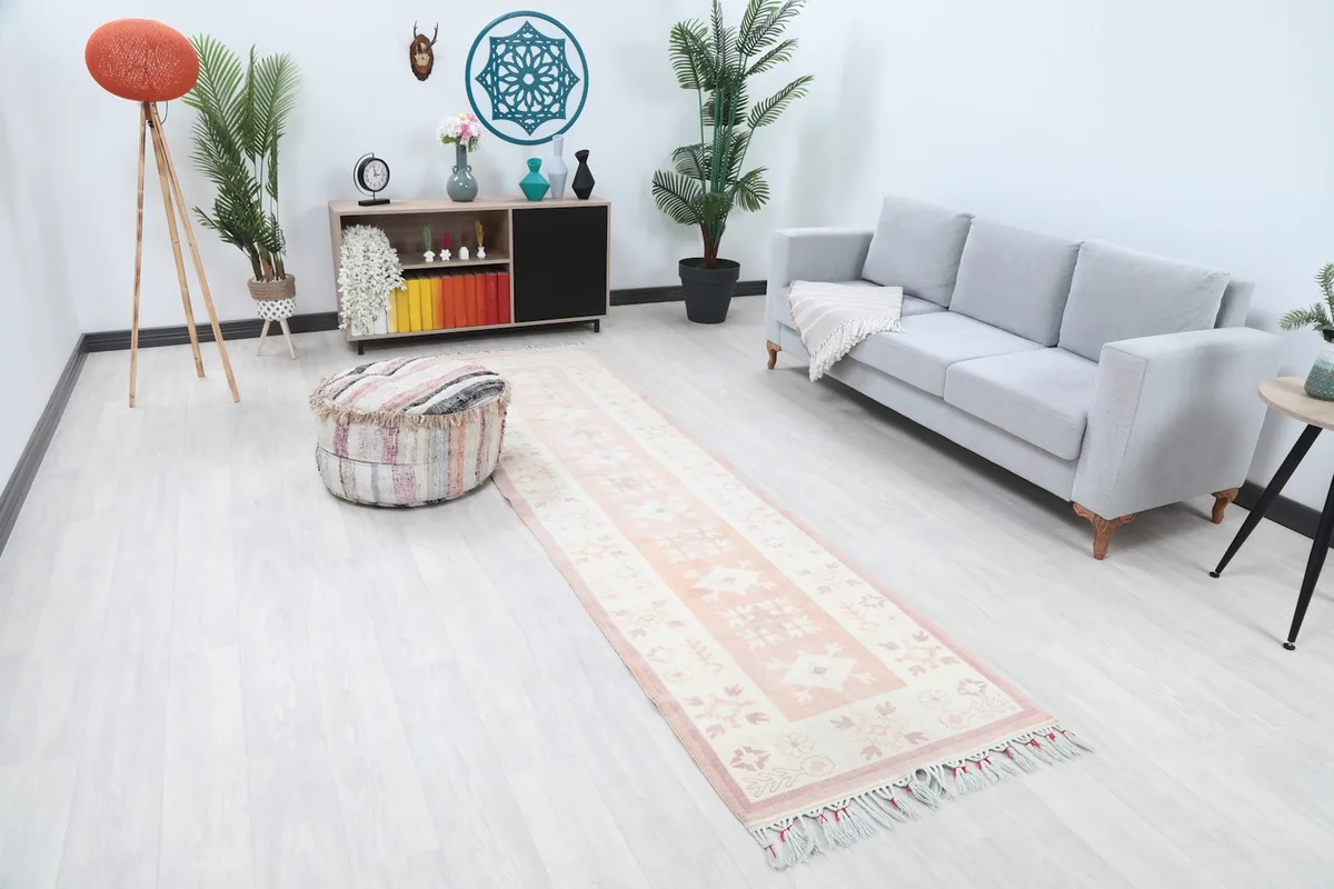 Overhead view of the rose and ivory runner rug laid out in a living room, showing its length and design.