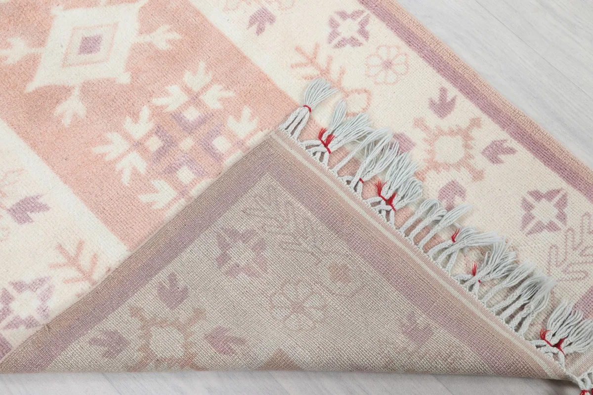 View of the back of the hand-knotted rug, revealing the foundation and construction, with a corner folded.
